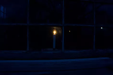 A candle glowing behind a window